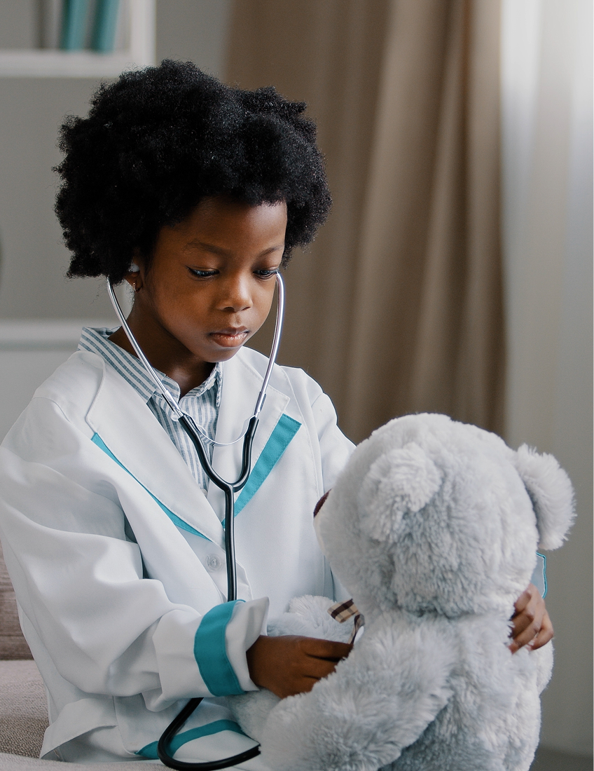 une petite fille déguisée en vétérinaire soigne son ours en peluche