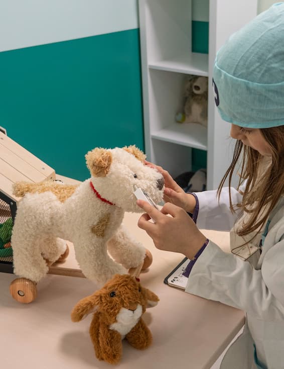 une petite fille joue au vétérinaire avec un chien en peluche à la Cité des Petits Rêveurs