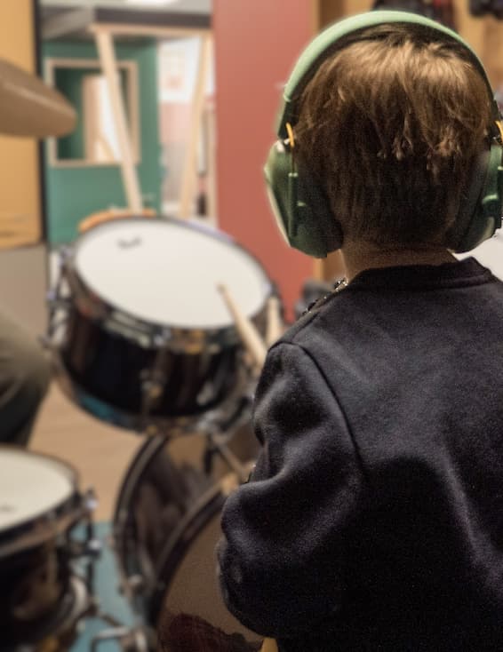 un petit garçon joue de la batterie à La Cité des Petits Rêveurs