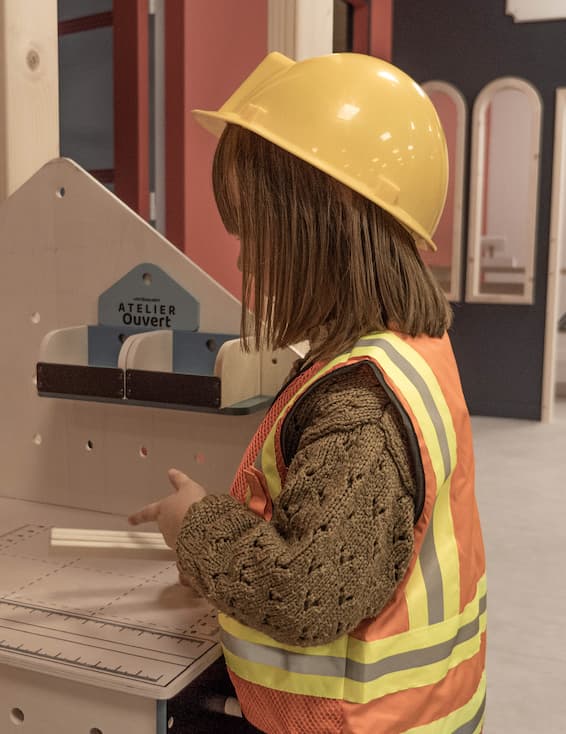 Une petite fille avec un casque de chantier à la Cité des Petits Rêveurs