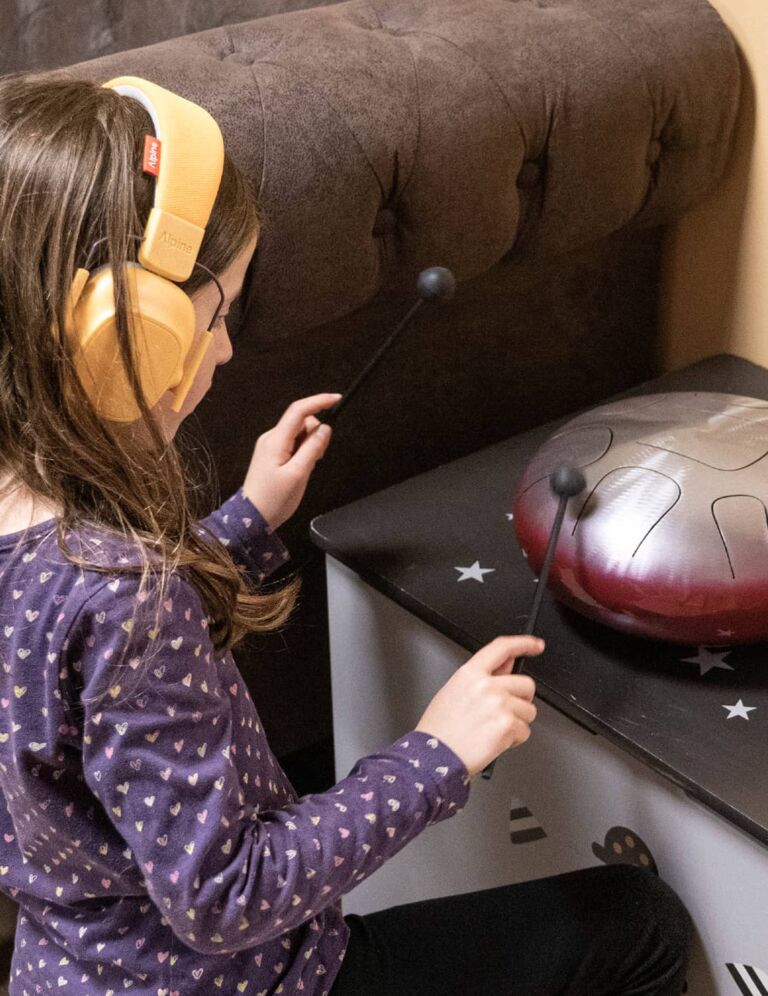 Une petite fille porte un casque pour se concentrer sur un instrument de musique à la Cité des Petits Rêveurs