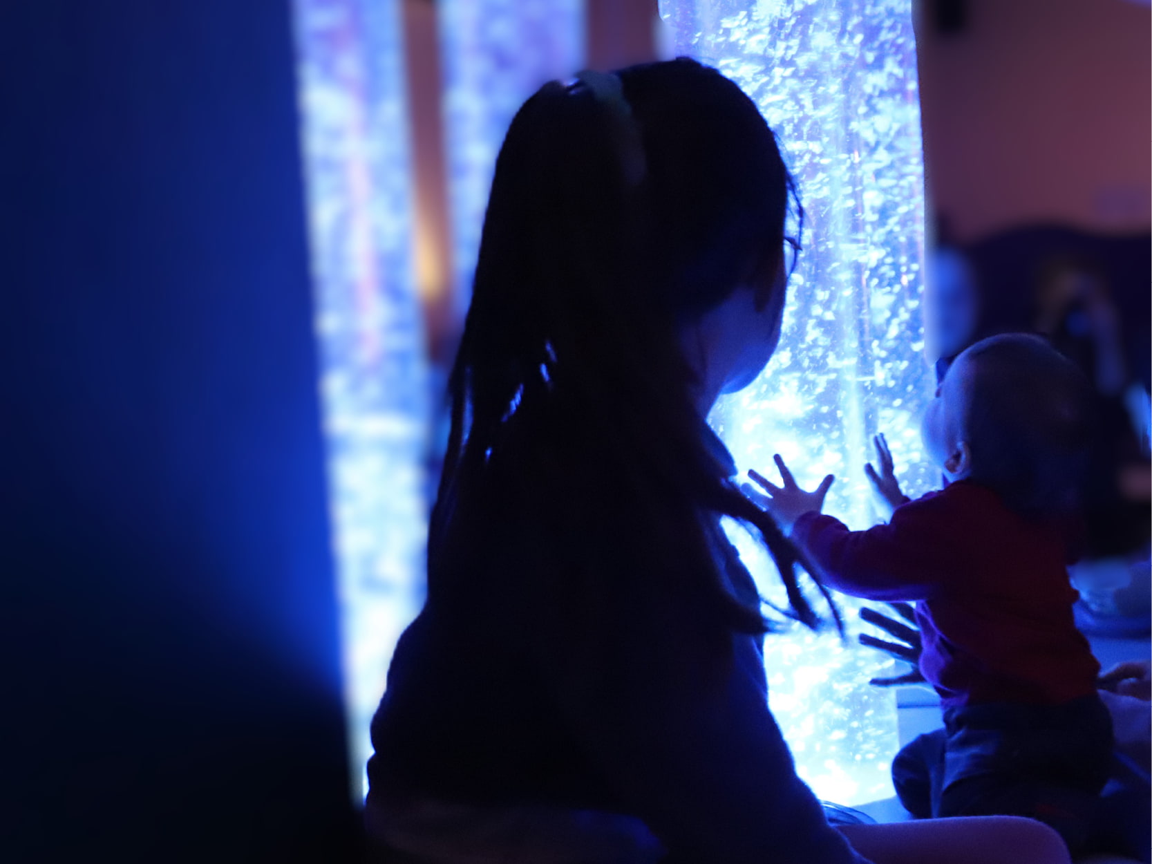 Une petite fille et un bébé jouent avec des installations lumineuses apaisantes à la Cité des Petits Rêveurs