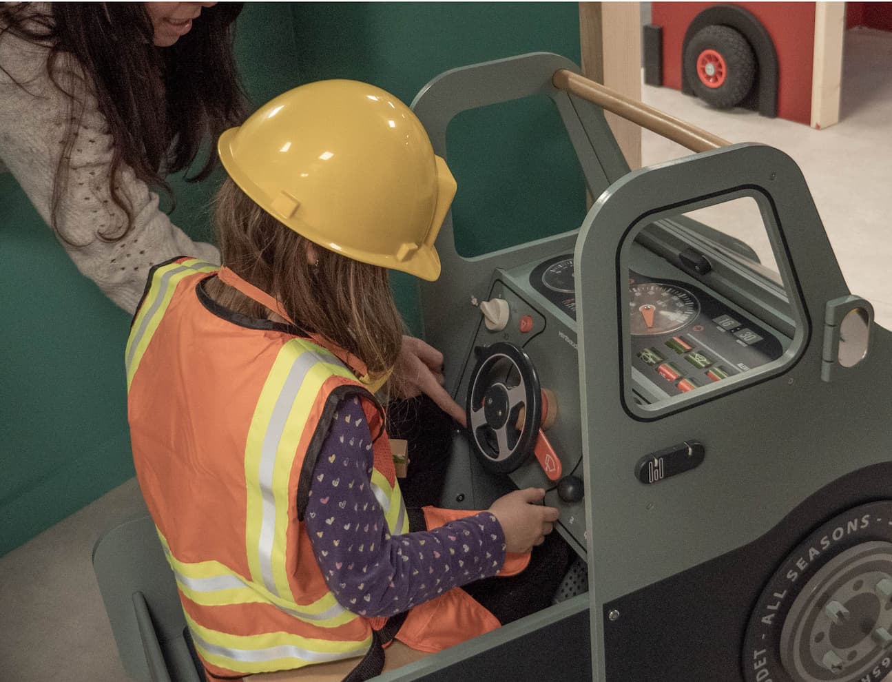 Petite fille habillée en tenue de chantier dans une voiture à la Cité des Petits Rêveurs